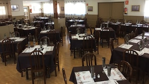 A restaurant with multiple tables set for dining, each with chairs and table settings. - The Hostal Iruñako (Burgos)