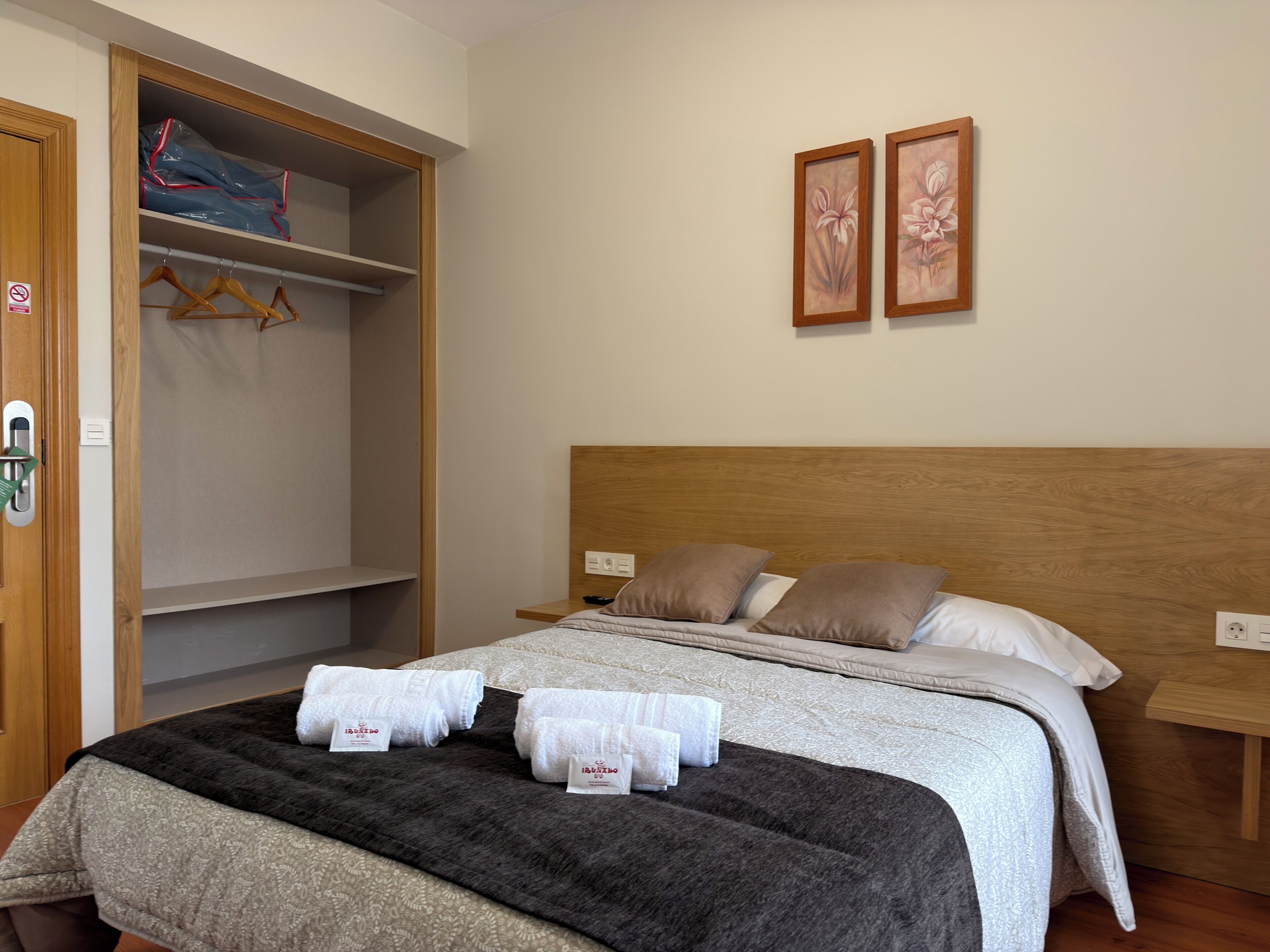 Een hotelkamer met een bed, een kledingkast en twee ingelijste foto's aan de muur.