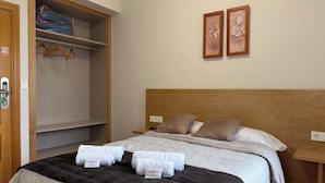 A hotel room with a bed, a wardrobe, and two framed pictures on the wall. - The Hostal Iruñako (Burgos)