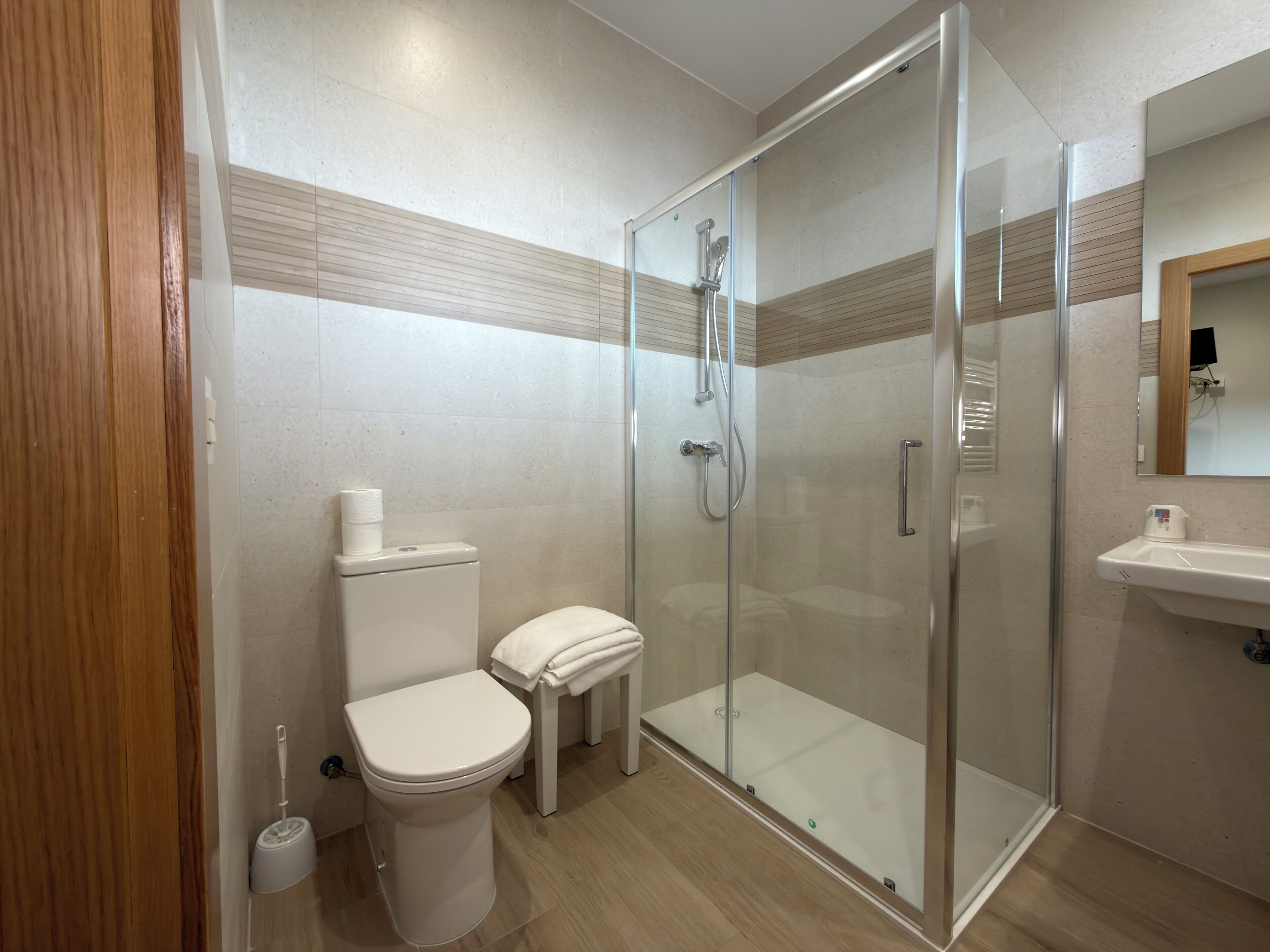 A modern bathroom with a toilet, a glass-enclosed shower, and a sink.