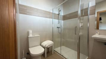 A modern bathroom with a toilet, a glass-enclosed shower, and a sink.