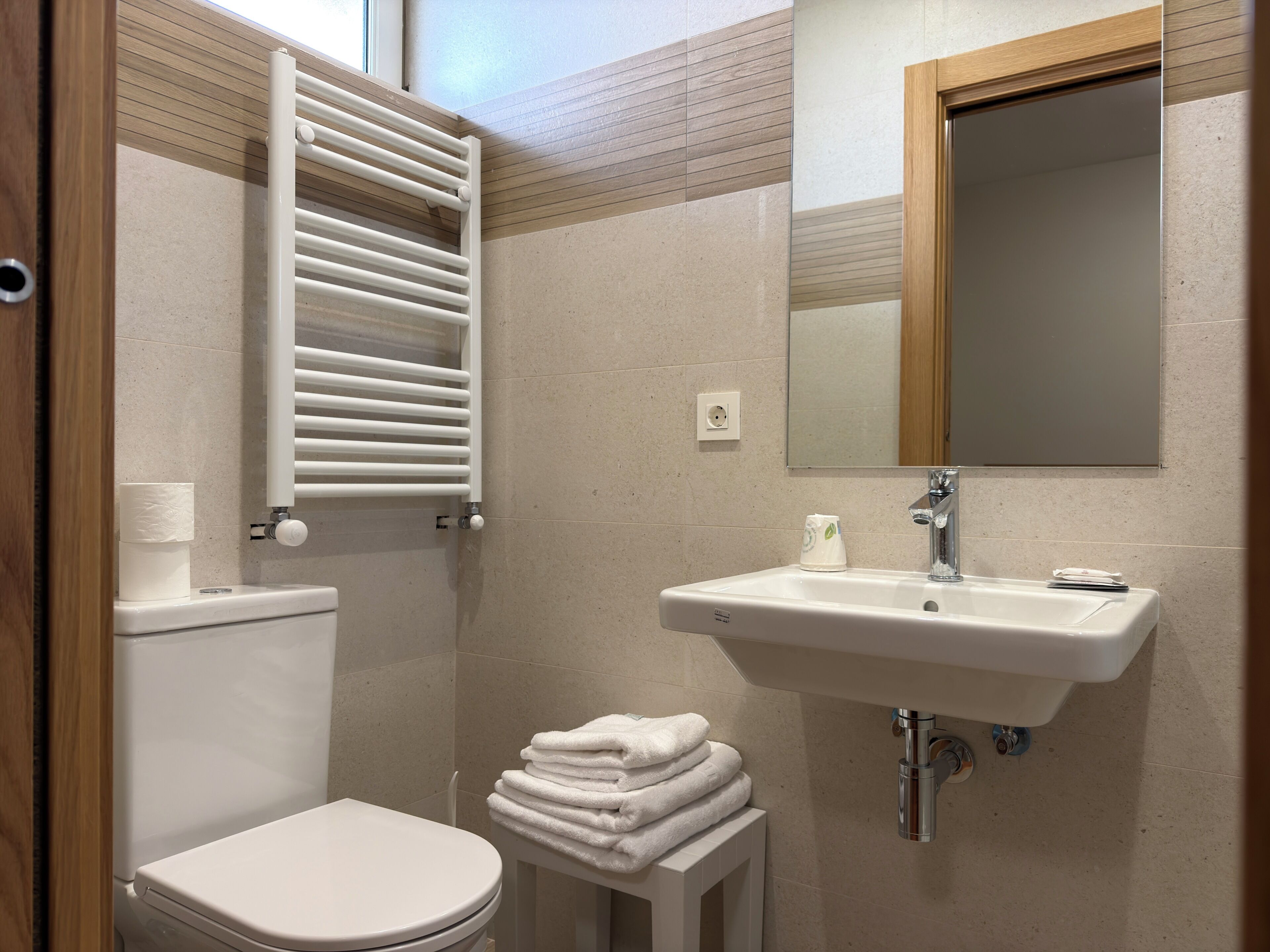 A bathroom with a toilet, a sink, a mirror, and a towel rack.