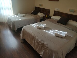 Habitación de hotel con dos camas, cada una con toallas dobladas y almohadas.