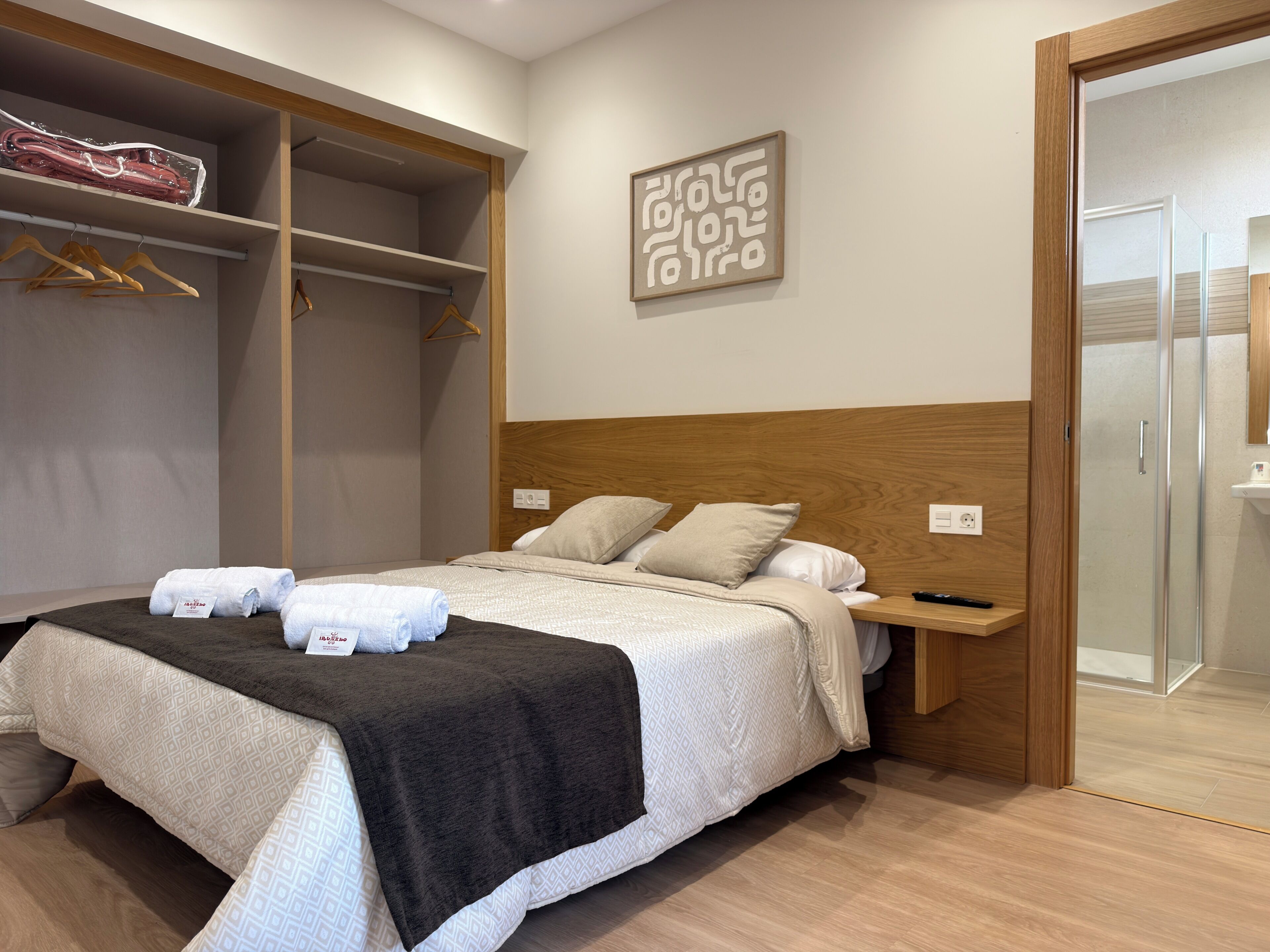 Une chambre d’hôtel comprenant un lit, une armoire, une table de chevet et un espace douche.
