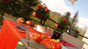 Mesa al aire libre con un bol de fresas, croissants, una taza y un vaso de agua.