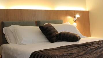 Une chambre d’hôtel avec un lit, des oreillers, une couverture et un luminaire fixé au mur.