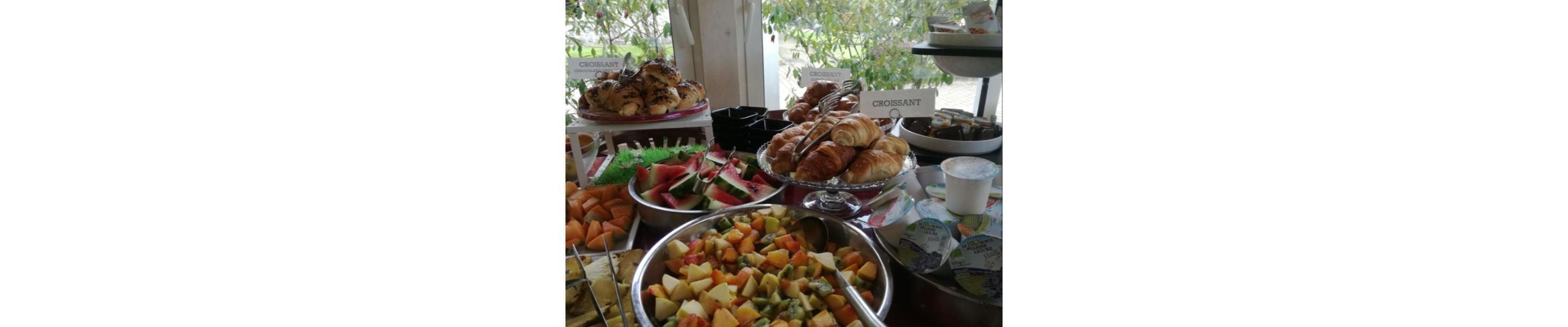 A buffet table with various food items including croissants, fruits, and vegetables.