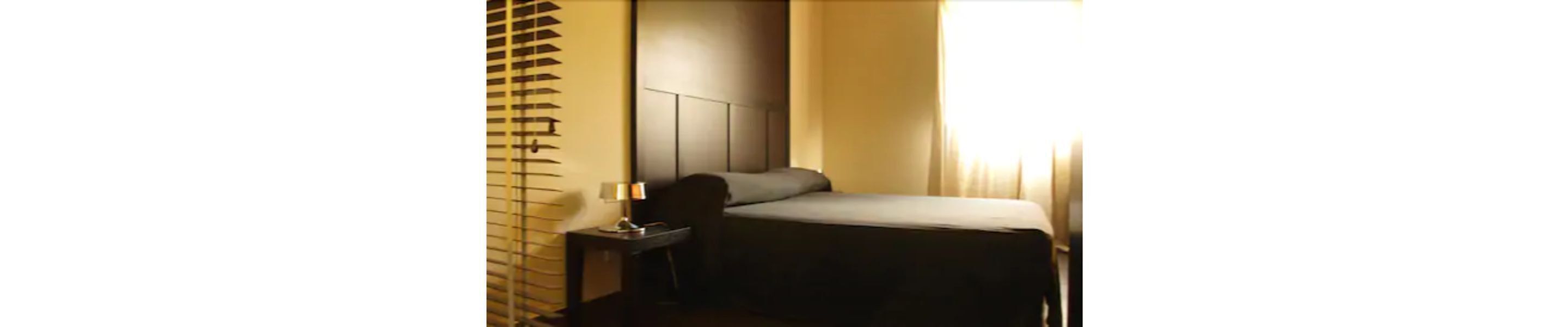 Ein Hotelzimmer mit einem Bett, einem Nachttisch und einer Lampe.