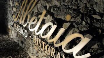 A stone wall with the words "Albergo" and "Albergo Alberghetti" carved into it.