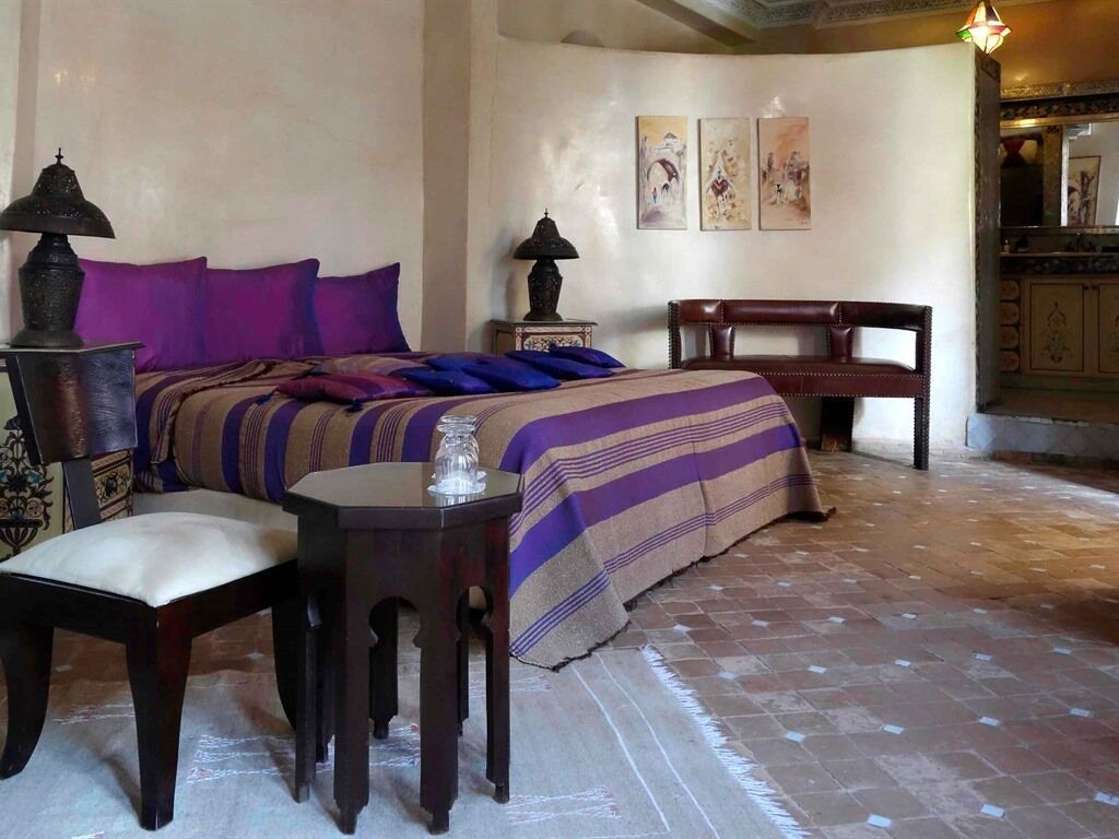 A bedroom with a bed, bedside tables, a chair, and a lamp.