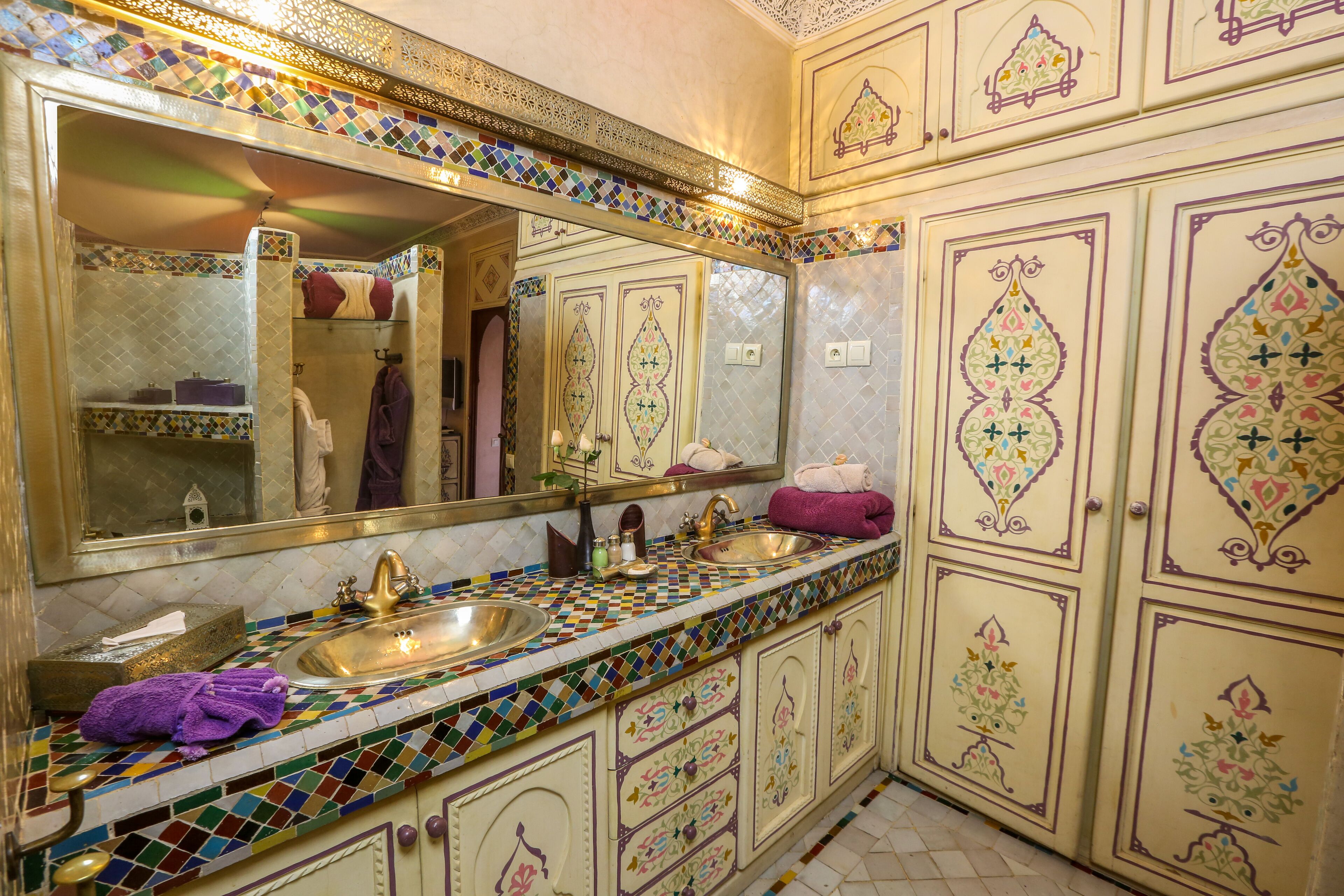 A bathroom with a tiled vanity, two sinks, and a large mirror.
