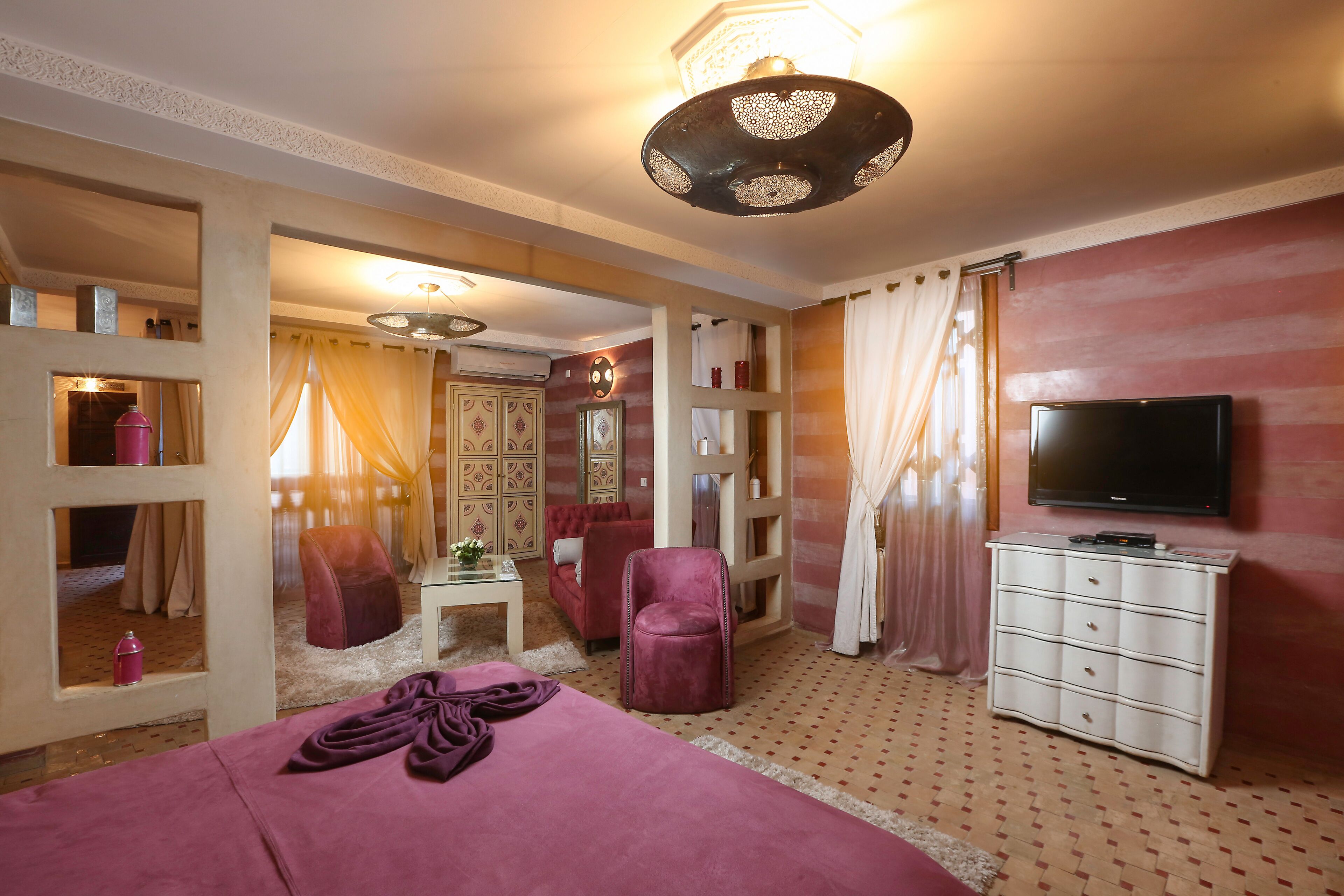 Une chambre d’hôtel avec un grand lit, une télévision, une commode et un coin salon comprenant une chaise et une petite table.