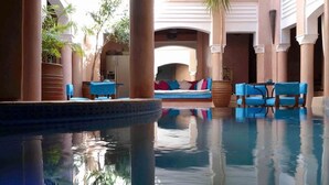 Area piscina con una poltrona prendisole, un divano e una palma.
