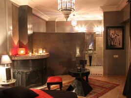 Una habitación con chimenea, candelabro, cama, una mesita y una alfombra.