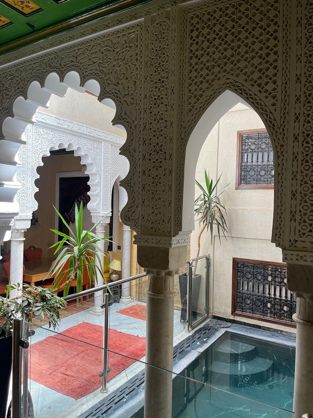 An interior courtyard with ornate arches, a glass-bottomed pool, and potted plants.