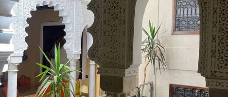An interior courtyard with ornate arches, a glass-bottomed pool, and potted plants.