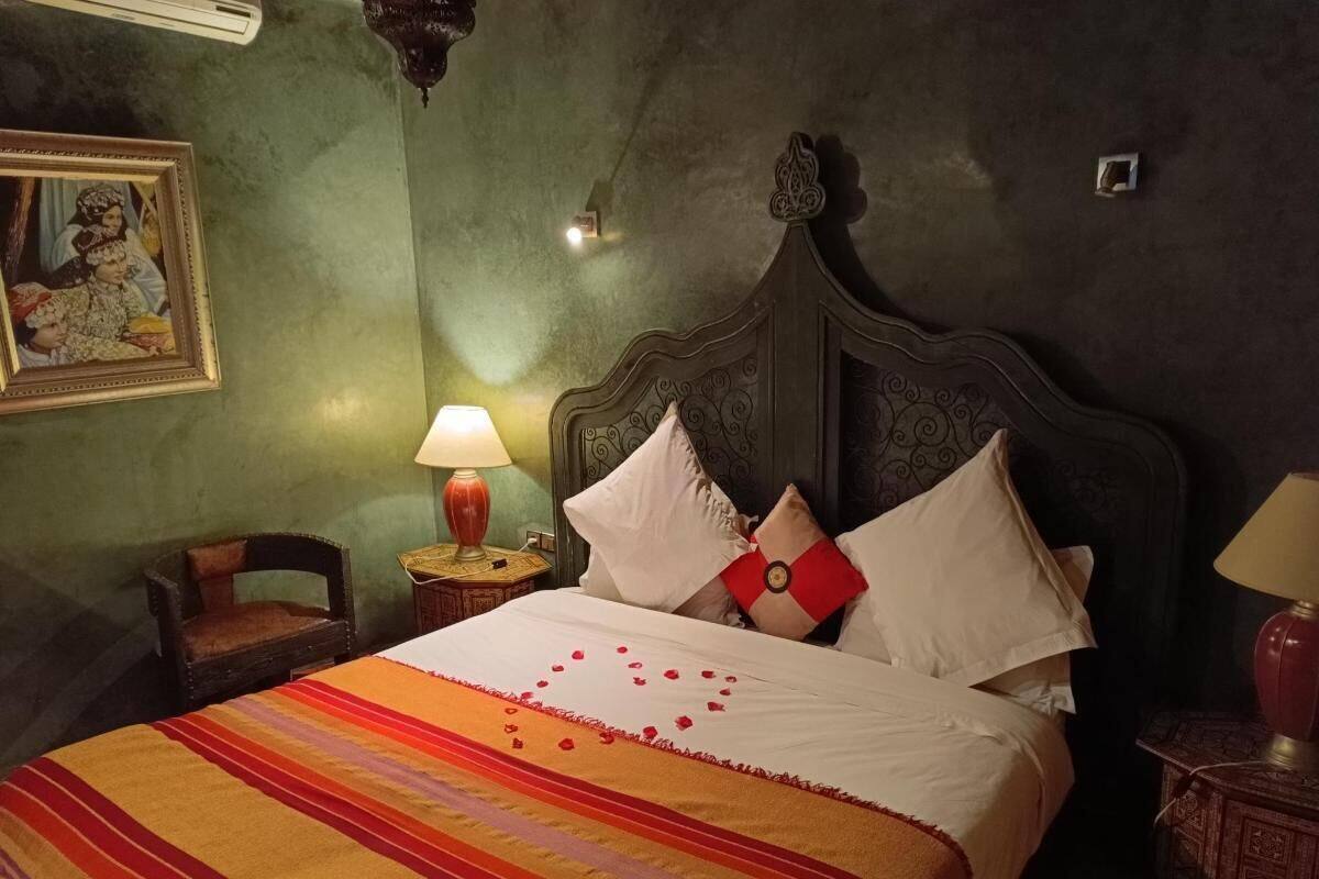 Una cama con colcha a rayas, una mesita de noche con lámpara y un cuadro en la pared.
