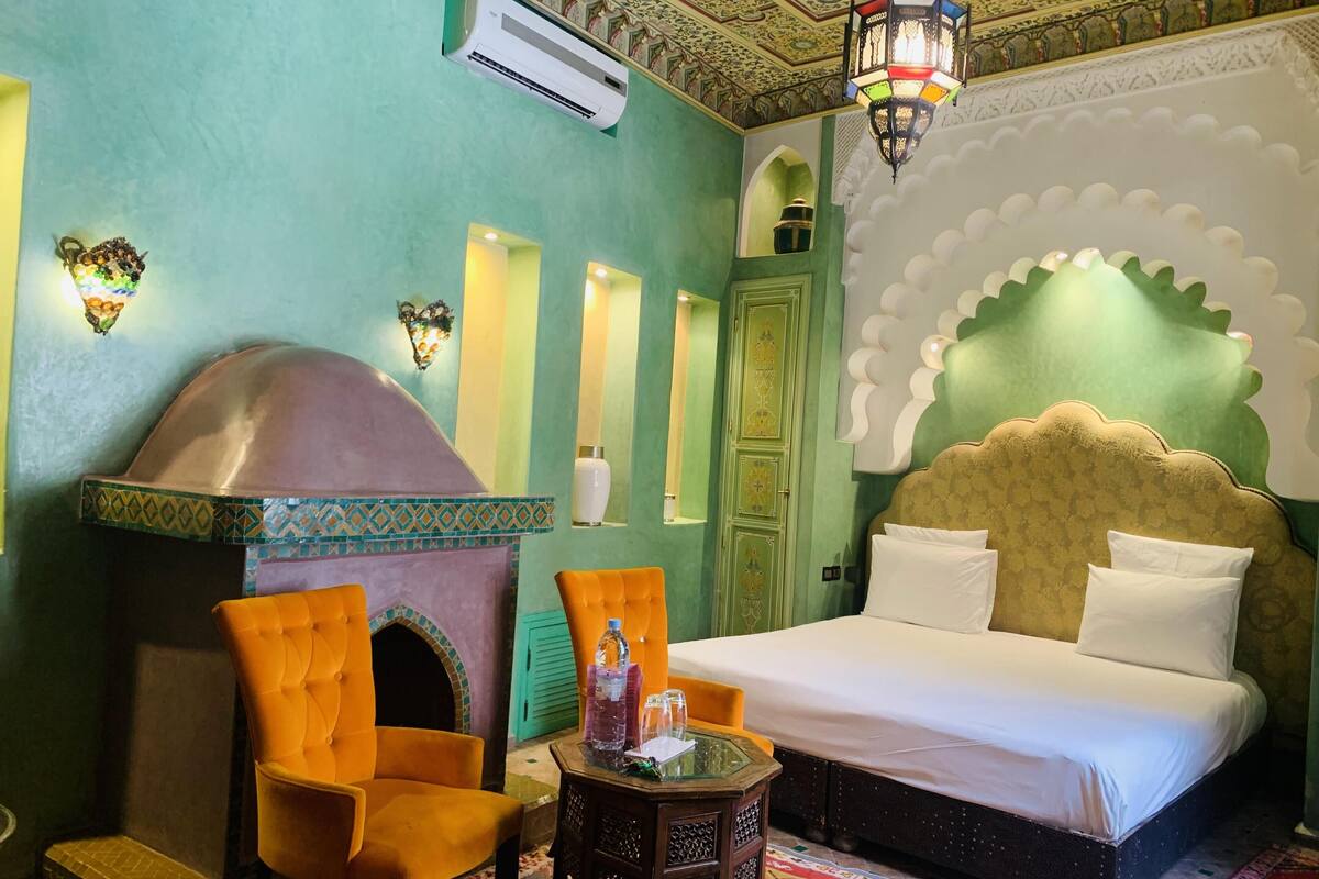 Habitación con cama, sofá, una mesita y una pared decorativa, además de un equipo de aire acondicionado.
