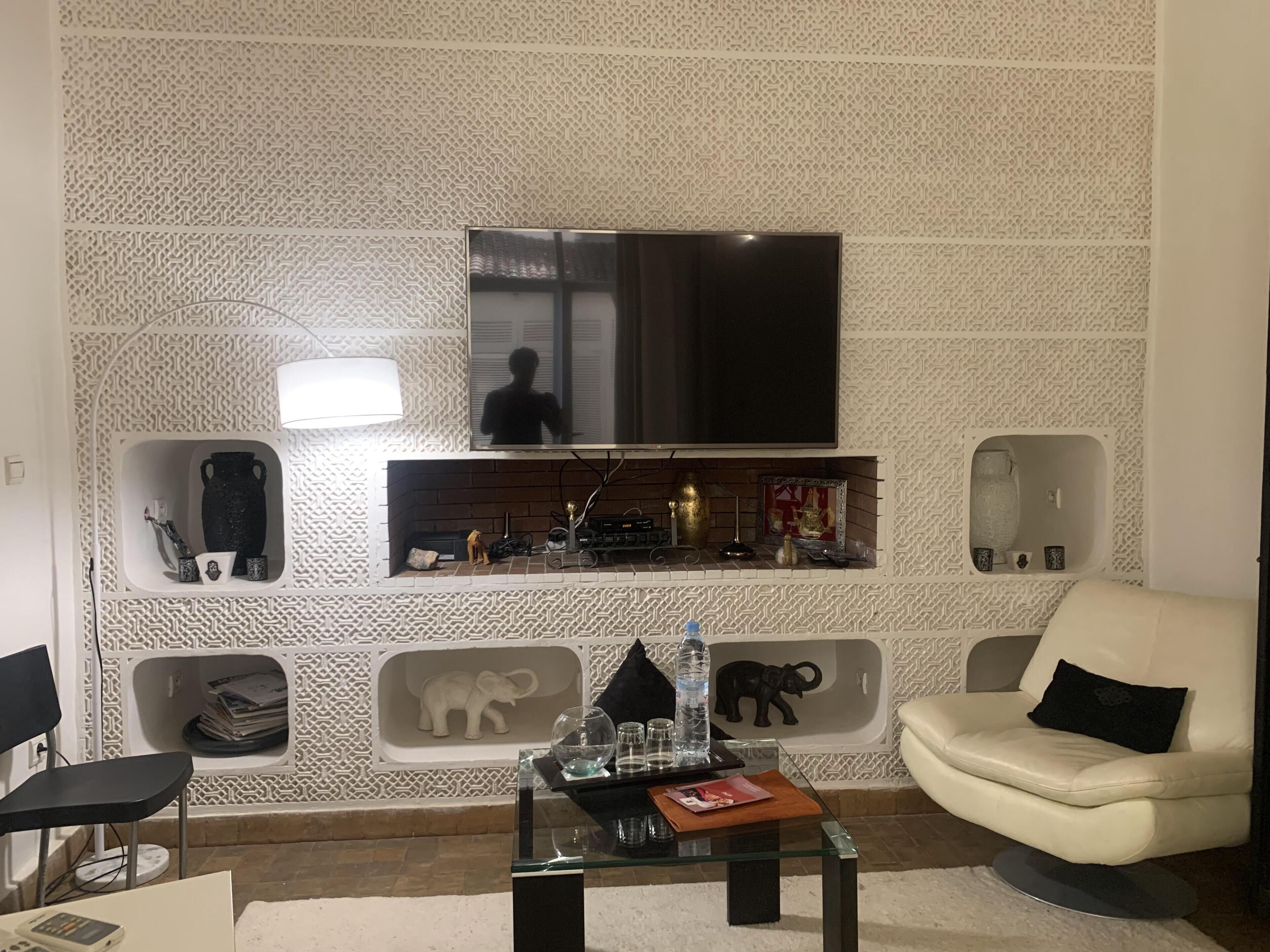 Un salon avec un téléviseur fixé au mur, un canapé, une table basse et des objets décoratifs disposés dans des niches intégrées.