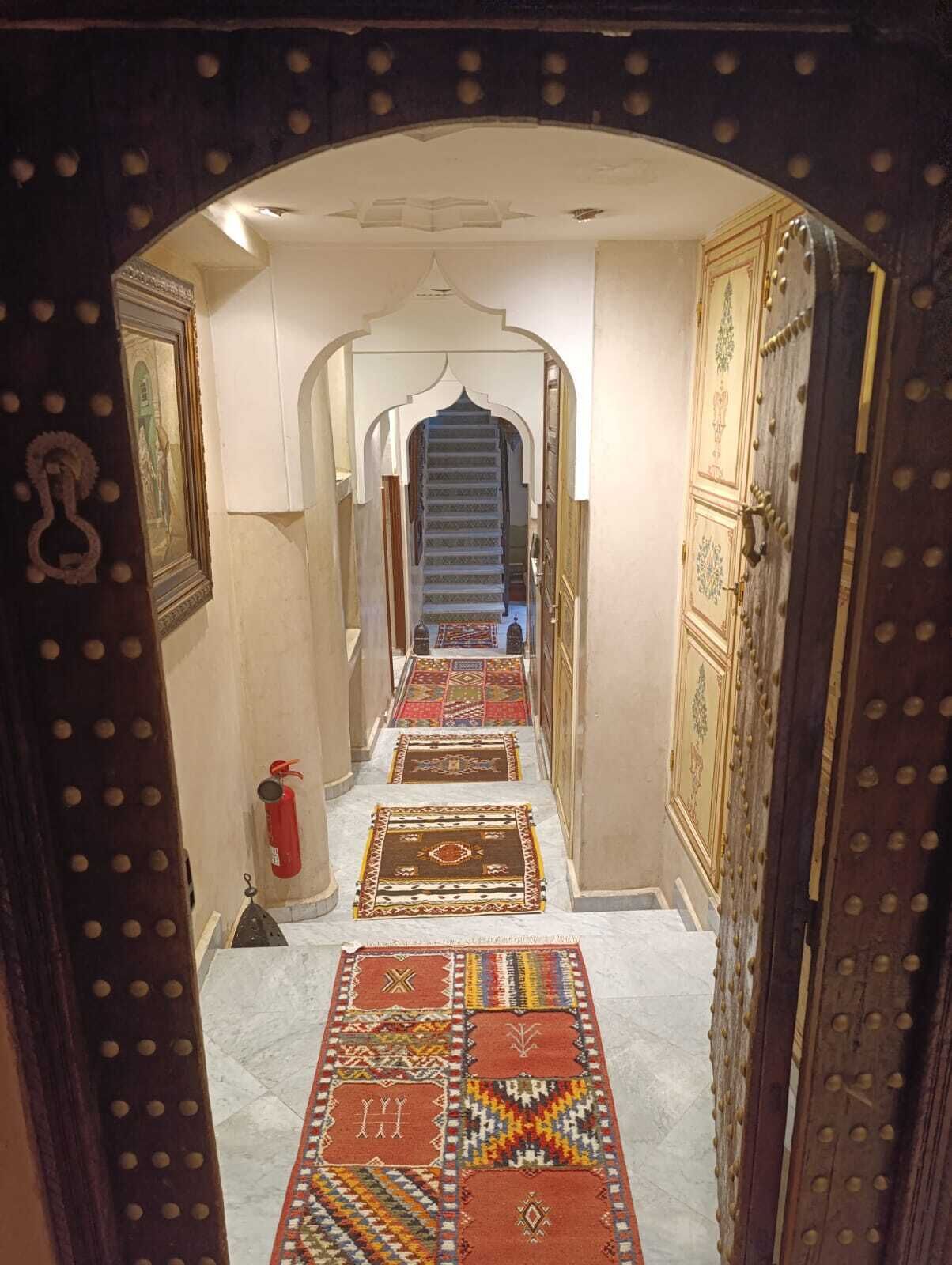 A hallway with patterned rugs, a staircase, and ornate doors.