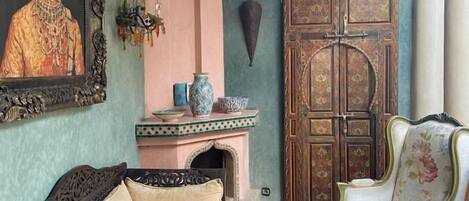 Une chambre traditionnelle avec un lit, une chaise, une lampe et un tableau accroché au mur.