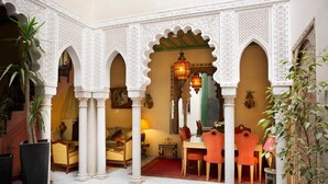 Un patio interior con arcos, una zona de comedor y un sofá.