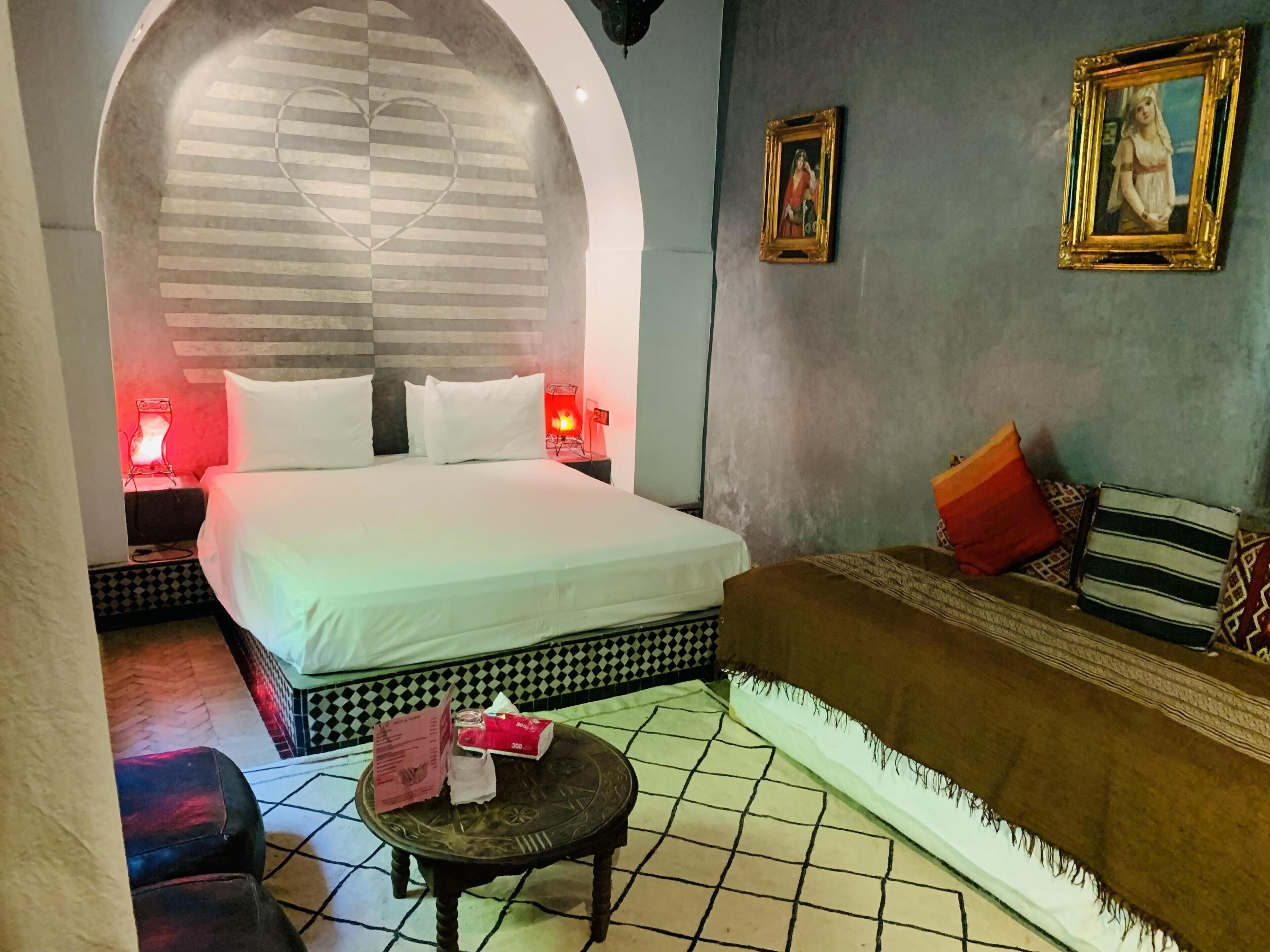 Ein Hotelzimmer mit Bett, Sofa, einem kleinen Tisch und einer Wand mit Herzdesign.