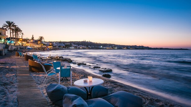 Uma área de estar à beira-mar com uma mesa e cadeiras, com vista para o oceano.