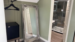 Une salle de bain avec une douche, un miroir et un meuble de rangement.