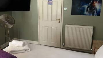 Una habitación de hotel con una cama, un radiador, un televisor montado en la pared y un cuadro de un astronauta.