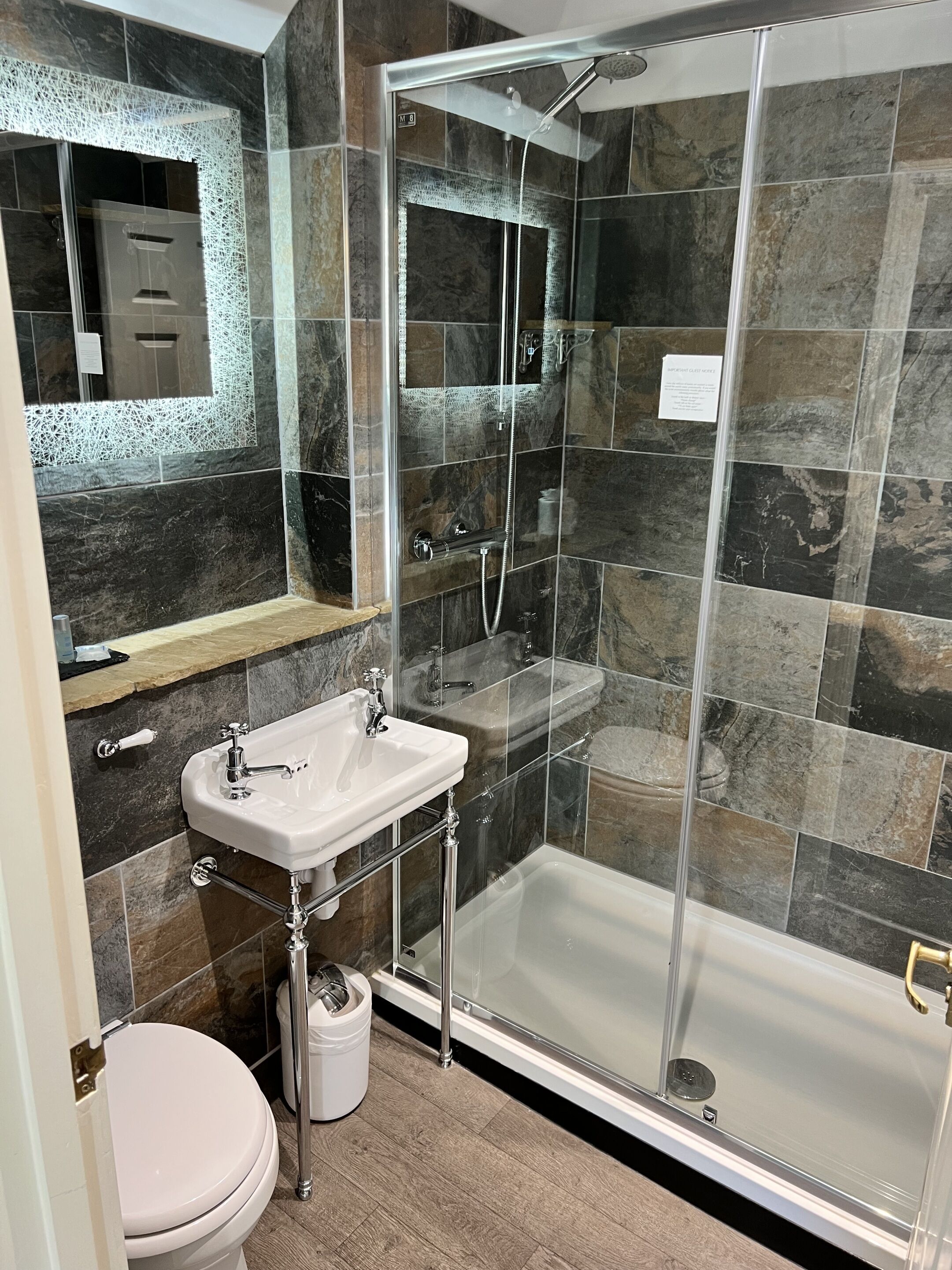 A modern bathroom with a glass-enclosed shower, a white sink, and a toilet.