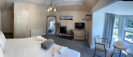A hotel room with a large bed, a dresser, a television, a chair, and a window with curtains.