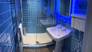 Une salle de bain moderne avec une douche à parois de verre, un lavabo blanc et des murs recouverts de carreaux bleus.