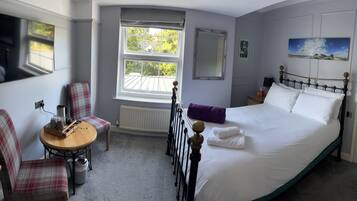 Une chambre à coucher avec un lit, une chaise, une petite table avec un plateau, une fenêtre et une porte.