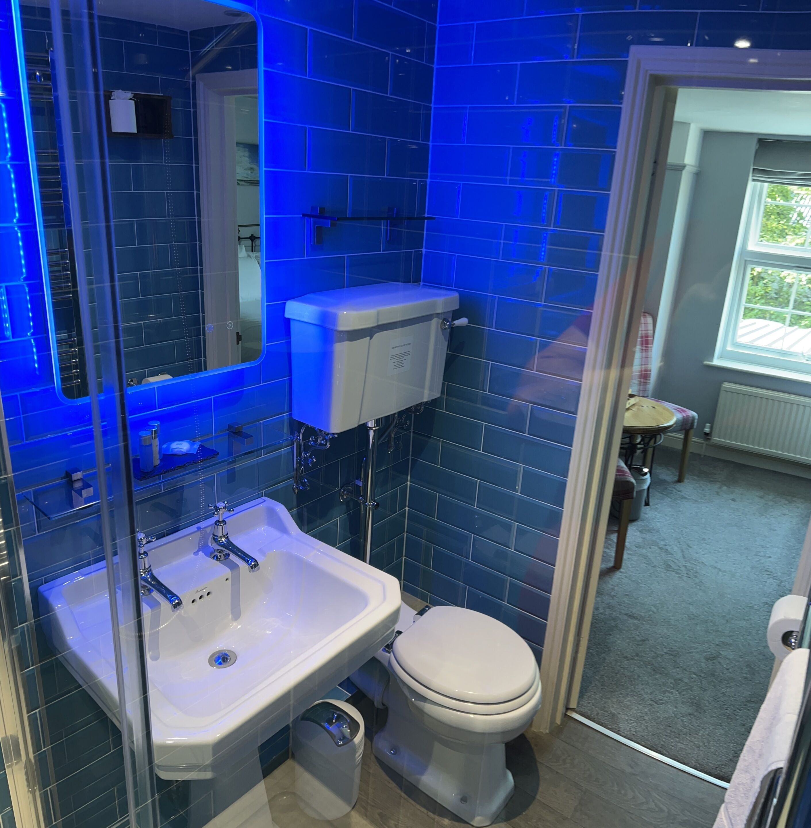 A bathroom with blue-tiled walls, a white sink, and a toilet.