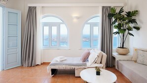 Un dormitori amb llit, una taula rodona i vista al mar.