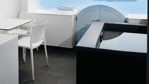 Habitació moderna amb una paret blanca corbada, una porta de vidre, una cadira blanca i una taula negra.