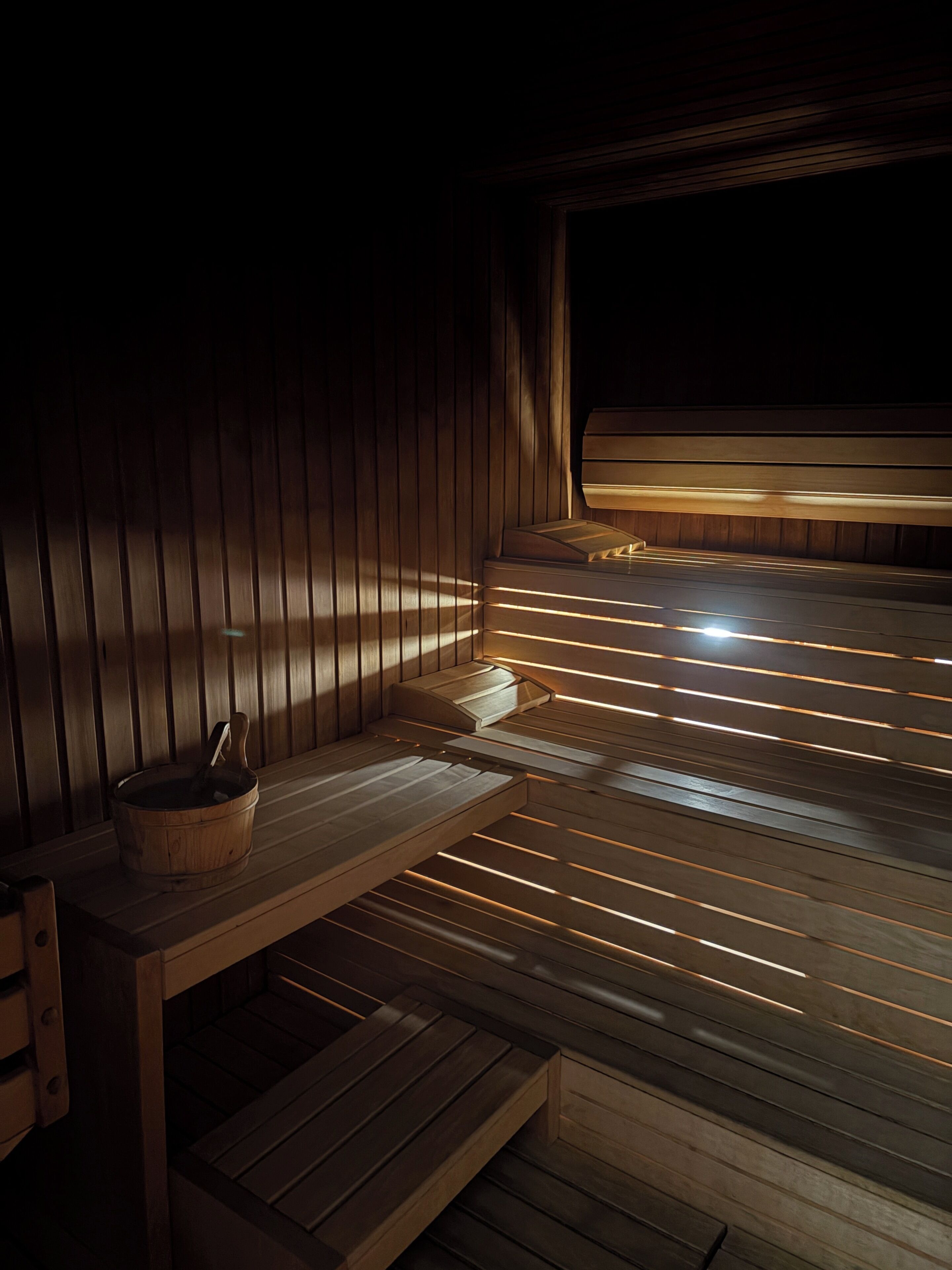 Una sauna con bancos de madera y un balde de madera.
