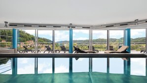 Zona de piscina con sillones de descanso y vistas del paisaje circundante.