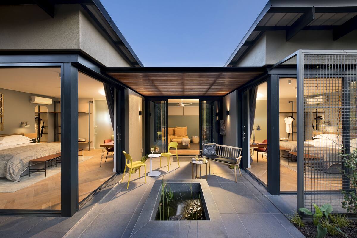 A modern hotel with a covered patio, a small pond, and a bedroom with a bed and a desk.