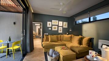 A modern living room with a sectional sofa, a dining area with yellow chairs, and a coffee table.