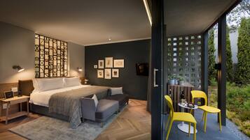 A modern bedroom with a bed, bedside tables, a desk, and a seating area with chairs and a table.