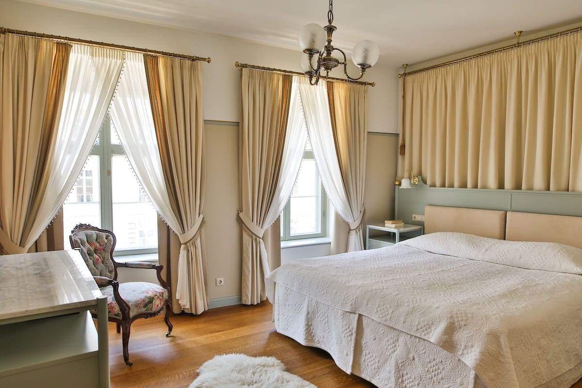 A bedroom with a large bed, a chair, a nightstand, and a chandelier.