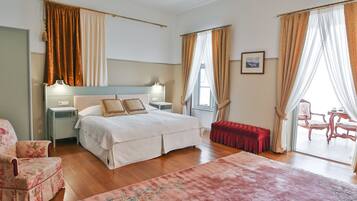 Quarto com cama, mesas de cabeceira, uma cadeira, um banco e vista para o exterior.