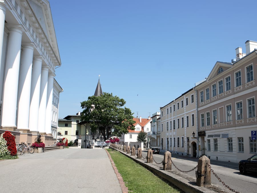 A street with buildings, a church, and a chain-link fence.