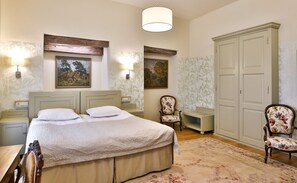 Un dormitorio con una cama, dos mesitas de noche, una silla, un armario y dos lámparas de pared.