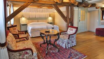 Een slaapkamer met een groot bed, een houten plafond en een vloerkleed met een rood- en blauw patroon.