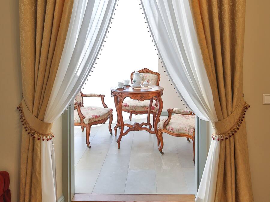 A room with a large window, a wooden chair, and a small table.