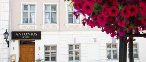 The exterior of the Antonius Hotel with a wooden double door, white-framed windows, and a sign above the entrance.