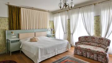A bedroom with a bed, a nightstand, a chair, and a chandelier.